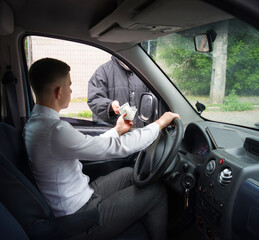 The driver of the car gives money to the homeless