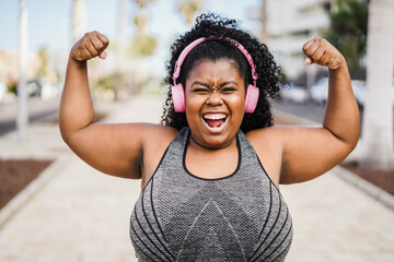 Happy curvy african woman celebrating during workout routine outdoor - Focus on face - obrazy, fototapety, plakaty