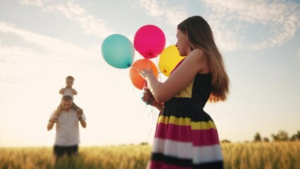 happy family on holiday in the park with balloons. father wears his son playing in a field with wheat in nature in the park. girl with balloons kid concept. friendly family dream at a birthday party
