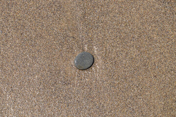 Fototapeta na wymiar A small stone rounded by the erosion of sand and waves