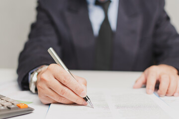 professional businessman wear suit hand holding pen writing and sign paperwork or document finance at office, man manager person handwriting paper on clipboard signature agreement approval business