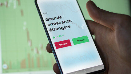 Un investisseur analyse un fonds etf grande croissance étrangère sur un graphique. Un téléphone affiche le cours de l'ETF. Texte en français francais Grande croissance étrangère