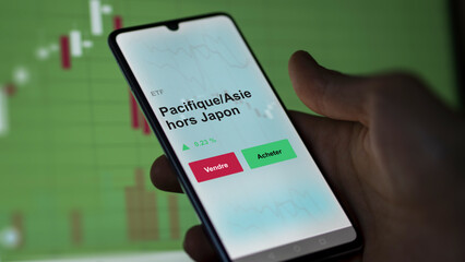 Un investisseur analyse un fonds etf pacifique/asie hors japon sur un graphique. Un téléphone affiche le cours de l'ETF. Texte en français francais Pacifique/Asie hors Japon