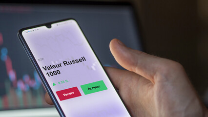 Un investisseur analyse un fonds etf valeur russell 1000 sur un graphique. Un téléphone affiche le cours de l'ETF. Texte en français francais Valeur Russell 1000