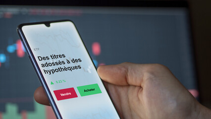 Un investisseur analyse un fonds etf des titres adossés à des hypothèques sur un graphique. Un téléphone affiche le cours de l'ETF. Texte en français francais Des titres adossés à des hypothèques