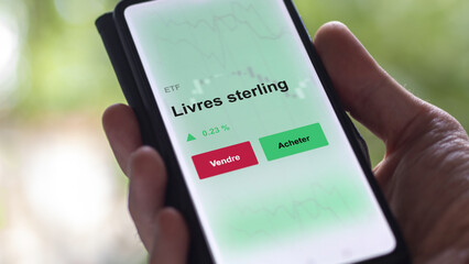 Un investisseur analyse un fonds etf livres sterling sur un graphique. Un téléphone affiche le cours de l'ETF. Texte en français francais livres sterling