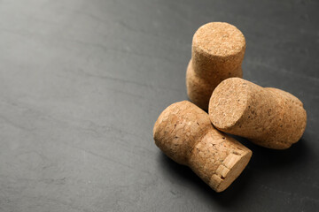 Sparkling wine corks on black table, closeup. Space for text