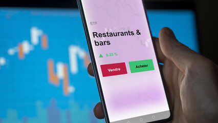 Un investisseur analyse un fonds etf restaurants & bars sur un graphique. Un téléphone affiche le cours de l'ETF. Texte en français francais Restaurants & bars