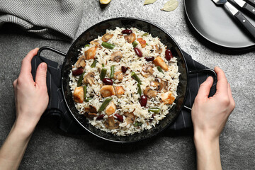 Woman with delicious rice pilaf at grey table, top view