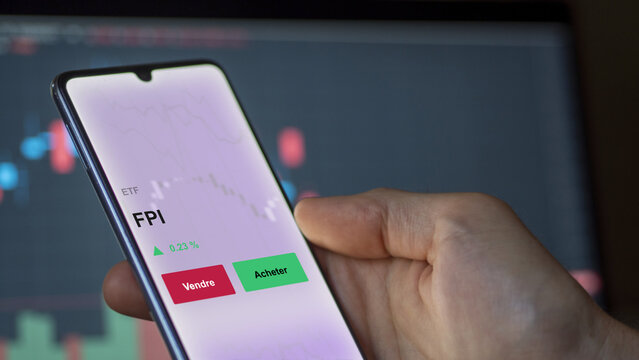 Un investisseur analyse un fonds etf fpi sur un graphique. Un t&eacute;l&eacute;phone affiche le cours de l'ETF. Texte en fran&ccedil;ais francais FPI