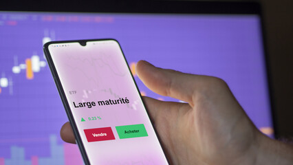 Un investisseur analyse un fonds etf large maturité sur un graphique. Un téléphone affiche le cours de l'ETF. Texte en français francais Large maturité