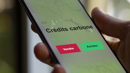 Un investisseur analyse un fonds etf crédits carbone sur un graphique. Un téléphone affiche le cours de l'ETF. Texte en français francais crédits carbone
