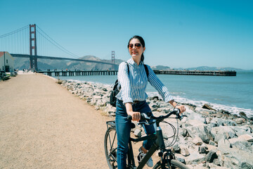 smiling asian female backpacker is enjoying beautiful scenery into the distance on bike at the...