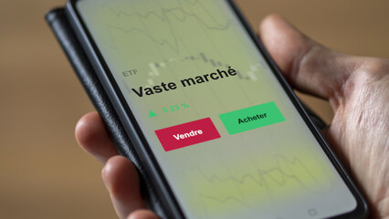 Un investisseur analyse un fonds etf vaste marché sur un graphique. Un téléphone affiche le cours de l'ETF. Texte en français francais Vaste marché