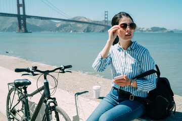 asian female traveler is looking into the distance while using gps app on phone during a break from...