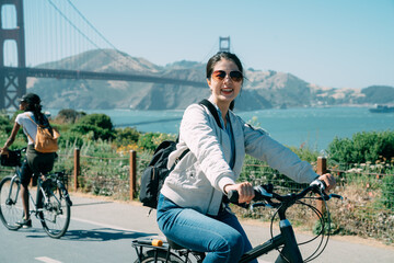cheerful asian girl is smiling at the camera on bike while taking a holiday on a clear day with...