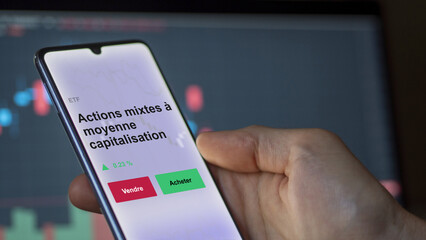 An investor's analyzing the materials etf fund on a screen. A phone shows the prices of Materials