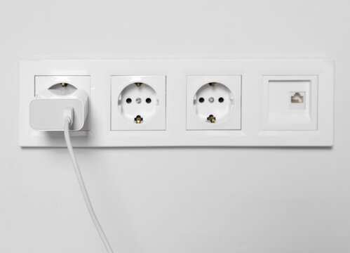 Charger adapter plugged in power socket indoors
