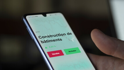 Un investisseur analyse un fonds etf construction de bâtiments sur un graphique. Un téléphone affiche le cours de l'ETF. Texte en français francais Construction de bâtiments