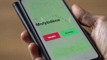 Un investisseur analyse un fonds etf molybdène sur un graphique. Un téléphone affiche le cours de l'ETF. Texte en français francais molybdène