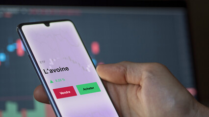 Un investisseur analyse un fonds etf l'avoine sur un graphique. Un téléphone affiche le cours de l'ETF. Texte en français francais L'avoine