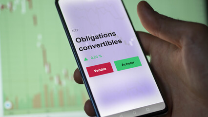 Un investisseur analyse un fonds etf obligations convertibles sur un graphique. Un téléphone affiche le cours de l'ETF. Texte en français francais Obligations convertibles
