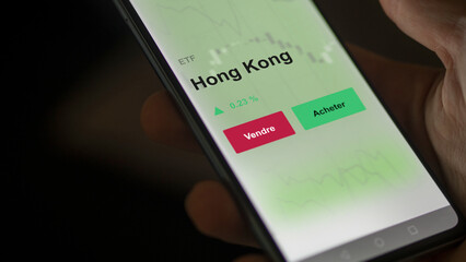 Un investisseur analyse un fonds etf hong kong sur un graphique. Un téléphone affiche le cours de l'ETF. Texte en français francais Hong Kong