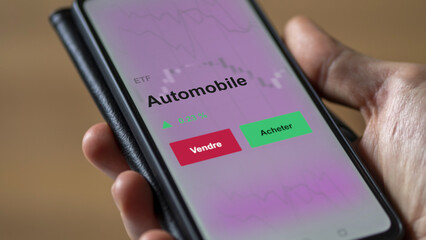 Un investisseur analyse un fonds etf automobile sur un graphique. Un téléphone affiche le cours de l'ETF constructeur voitures. Texte en français francais 
