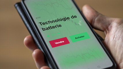 Un investisseur analyse un fonds etf technologie de batterie sur un graphique. Un téléphone affiche le cours de l'ETF. Texte en français francais Technologie de batterie