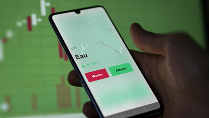 Un investisseur analyse un fonds etf eau sur un graphique. Un téléphone affiche le cours de l'ETF. Texte en français francais Eau