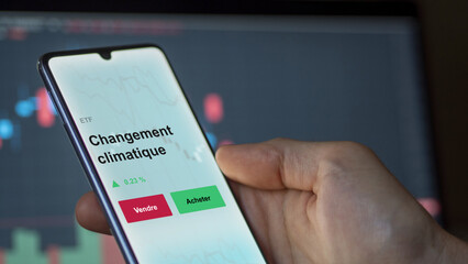 Un investisseur analyse un fonds etf changement climatique sur un graphique. Un téléphone affiche le cours de l'ETF. Texte en français francais Changement climatique