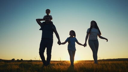 people in the park. happy family walking silhouette at sunset. mom dad and daughters walk holding hands in sun the park. happy family childhood dream concept. parents and children go back silhouette