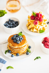 Summer breakfast. Homemade baked ricotta pancakes and Belgian waffles with fresh berries on white wooden table