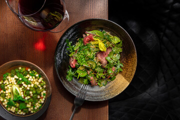 Salad with meat, arugula and soup and glass of wine