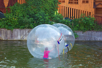 Fun game on the water zorbing, children swim and have fun in a transparent inflated plastic balloon, active pastime on vacation