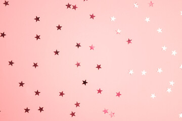 Pink star shaped glitter confetti on pink background. Festive flat lay holiday pastel backdrop.