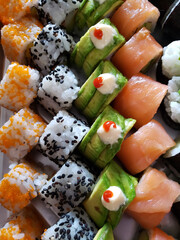 Closeup studio shot of bright, colorful, fresh and healthy bite sized, delicious sushi rolls, arranged in rows according to type.