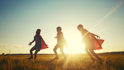 team superhero. a group of children are running across the field in a superhero costume with a...