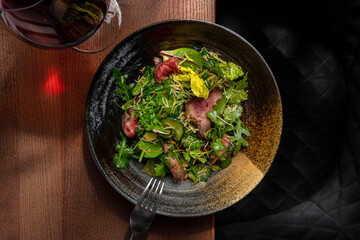 Salad with meat, arugula, frisse salad and wine