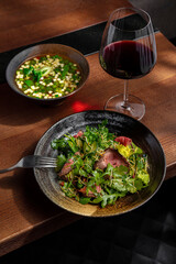 Salad with meat, arugula and soup and glass of wine