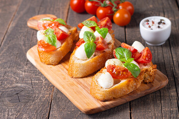 Tomato, basil and cheese fresh made caprese bruschetta. Italian tapas, antipasti with vegetables, herbs and oil on grilled ciabatta and baguette bread. Sandwich.