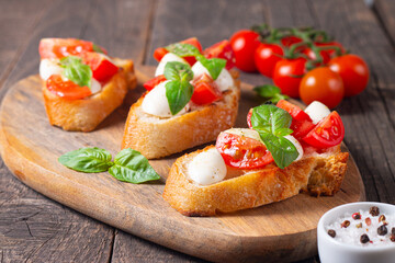 Tomato, basil and cheese fresh made caprese bruschetta. Italian tapas, antipasti with vegetables, herbs and oil on grilled ciabatta and baguette bread. Sandwich.