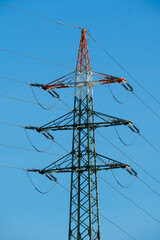 High voltage tower with electricity transmission power lines against blue sky