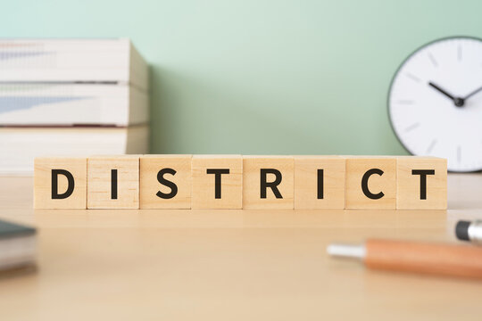 地区・地域のイメージ｜「DISTRICT」と書かれたブロックが置かれたデスク
