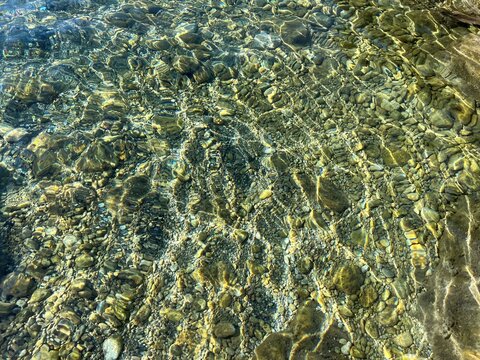 Smooth pebbles and stones on seabed in clear transparent sea water.