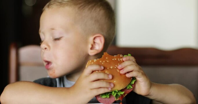 Little boy in fast food cafe eats burger. little kid eating burger. 