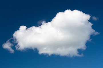 A white cumulus cloud against a dark blue daytime sky. A high resolution.