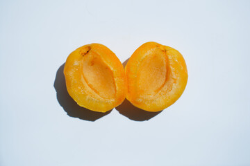 Apricot broken without a bone lies on a white background in daylight, close-up of an appetizing fruit