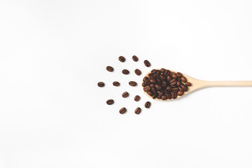 Composition of coffee beans on wooden spoon in flat lay. The concept of preparing a natural tasty drink, oriented to the right side. Top view with copy space.