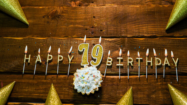 golden letters of the candle with the number happy birthday, the background of the pie with candles happy birthday on the background of brown stranded boards. Postcard Happy birthday 79